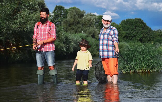 Gelukkige grootvader en kleinzoon vissen op de rivier vader zoon en grootvader ontspannen samen