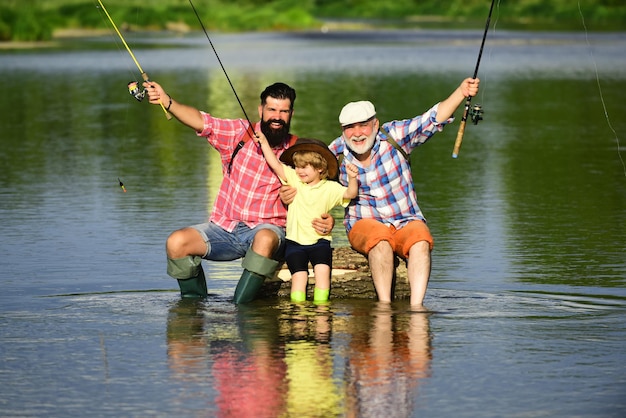 Gelukkige grootvader met zoon en kleinzoon die plezier hebben in riviermannendag vader zoon en grootvader op fi