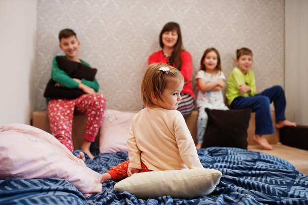 Gelukkige grote familie heeft samen plezier in de slaapkamer. Grote familie ochtend concept. Moeder met vier kinderen draagt thuis een pyjama in bed.