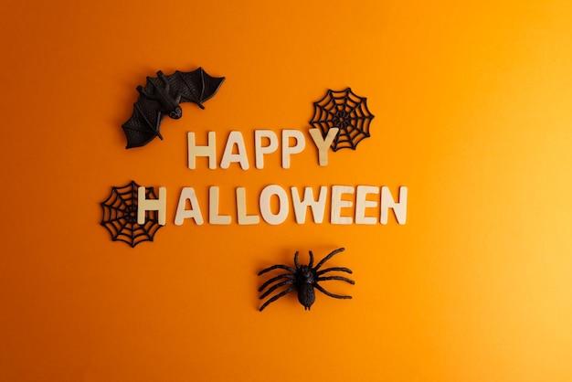 Gelukkige Halloween lettering op oranje achtergrond met Halloween decor spinnen en spinnenweb