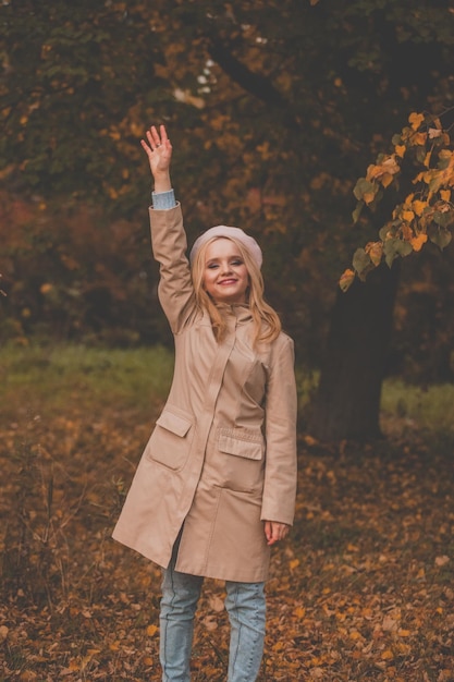 Gelukkige herfst vrouw zwaaien zeggen hallo en glimlachen buiten vriendelijk welkom gebaar