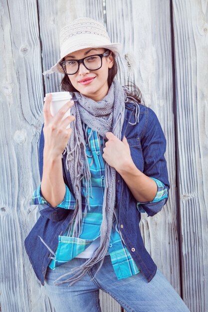 Gelukkige hipster die een kop in haar hand houdt