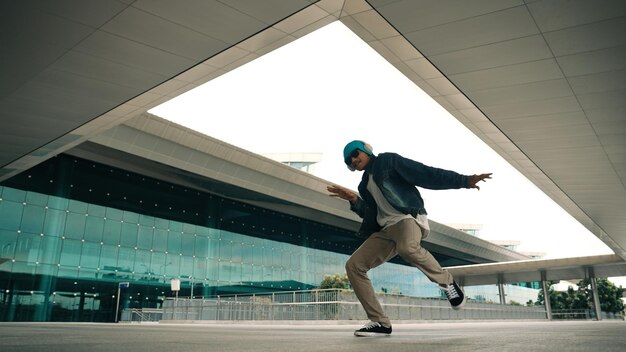 Gelukkige hipster oefening b boy dans met stijlvolle doek bij het gebouw Sprightly