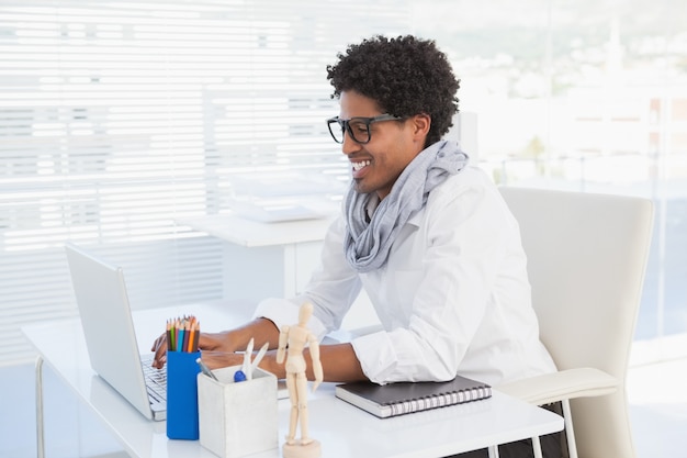 Gelukkige hipsterzakenman die bij zijn bureau werkt