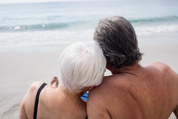 Gelukkige hogere paarzitting op strand