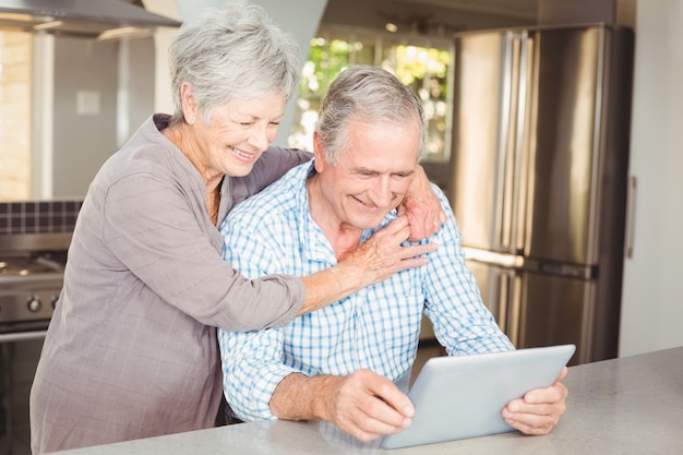 Gelukkige hogere vrouw die de mens omhelst die tablet gebruikt