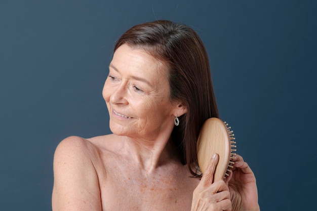 Gelukkige hogere vrouw die haar haar borstelt