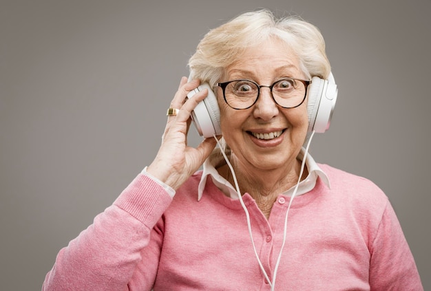 Gelukkige hogere vrouw die hoofdtelefoons draagt