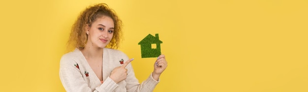 Gelukkige huiskoper een jong meisje houdt een model van een groen huis in haar handen het concept van groene energie-ecologie