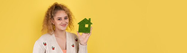 Gelukkige huiskoper Een jong meisje houdt een model van een groen huis in haar handen Het concept van groene energie-ecologie