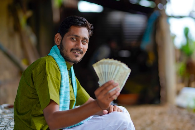 Foto gelukkige indiase boer die thuis geld toont.