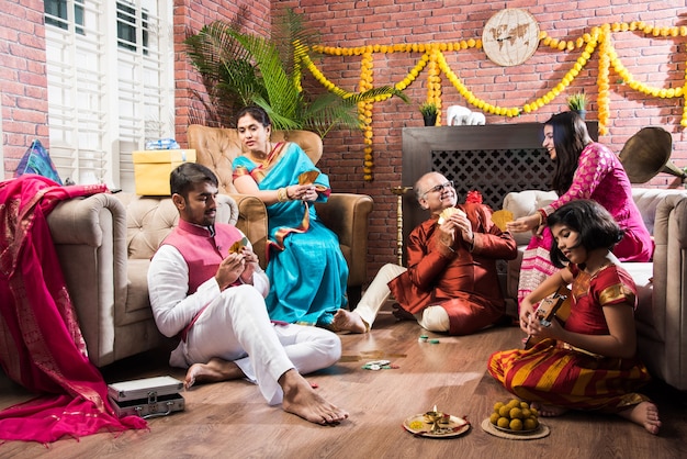 Gelukkige Indiase familie die tiener patti of drie kaarten speelt op diwali-festivalnacht in traditionele kleding thuis