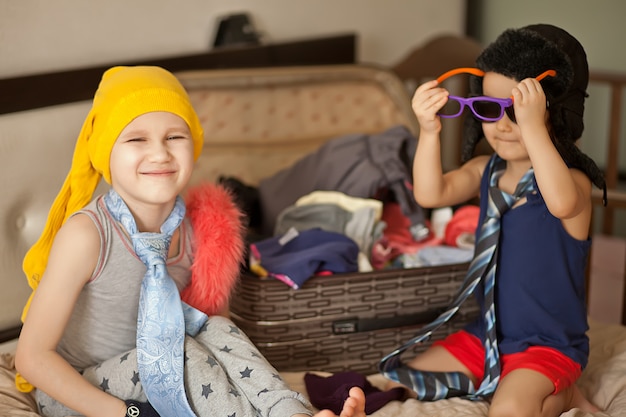 Gelukkige jeugd. Leuk meisje en jongen spelen in een mode en het dragen van een zonnebril, cowboyhoed. Schattige kinderen plezier binnenshuis.