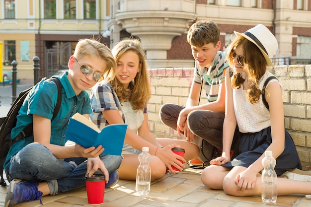 Gelukkige jeugdvrienden of middelbare scholieren hebben plezier, praten, lezen telefoon