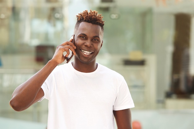 Gelukkige jonge Afrikaanse mensenkerel die een telefoongesprek en het glimlachen maakt