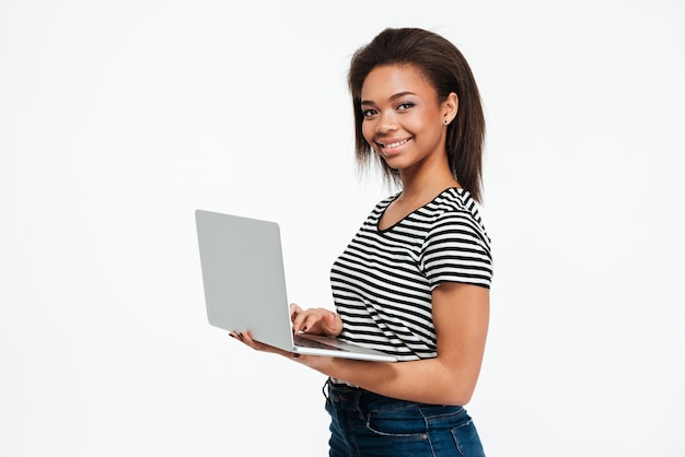 Gelukkige jonge Afrikaanse vrouw die laptop computer met behulp van.