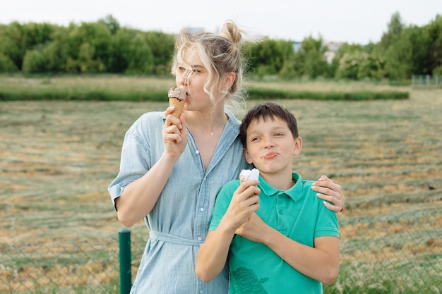 Gelukkige jonge alleenstaande moeder met haar tienerzoon die plezier heeft op een zomerdag. Familie ijs eten en lachen