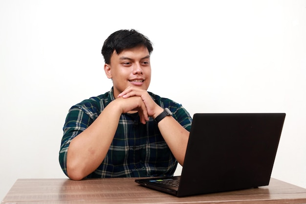 Gelukkige jonge Aziatische man met iets op zijn laptop met een glimlachende gezichtsuitdrukking