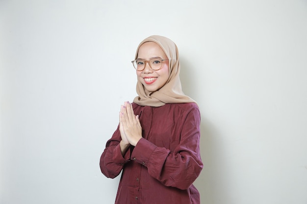 Gelukkige jonge Aziatische Moslimvrouw die glazen draagt die met beide geïsoleerde handen begroeten