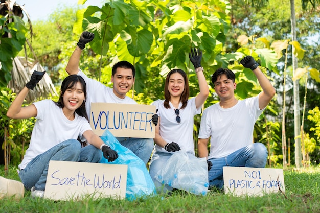 Gelukkige jonge Aziatische studenten, diverse vrijwilligers houden een campagneschild vast voor het schoonmaken van het park.