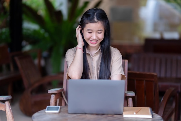 Gelukkige jonge aziatische tienermeisje college student met een laptop computer schrijven op een pc werken