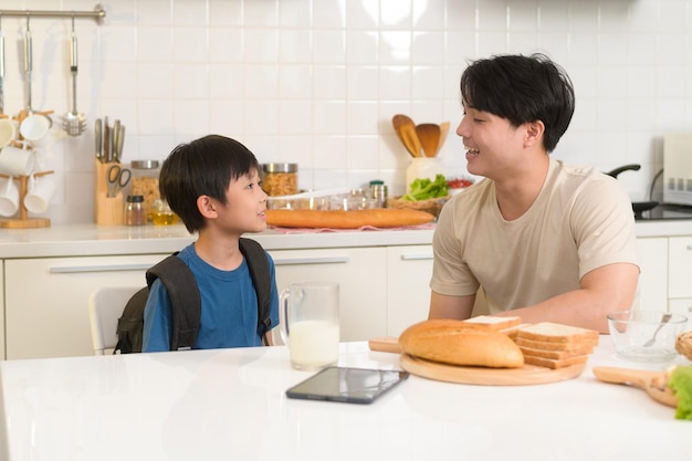 Gelukkige jonge aziatische vader die zijn zoon aanmoedigt om naar school te gaan