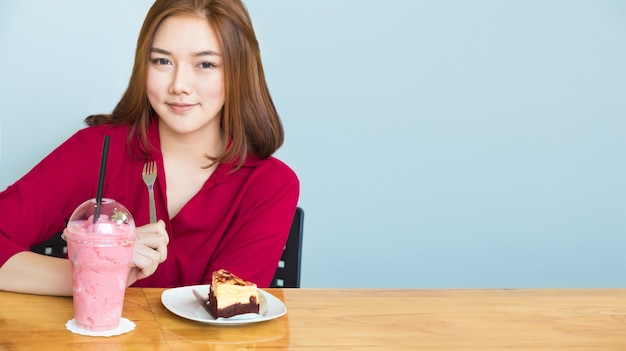 Gelukkige jonge Aziatische vrouw die bij een lijst met haar voedsel op lijst situeren