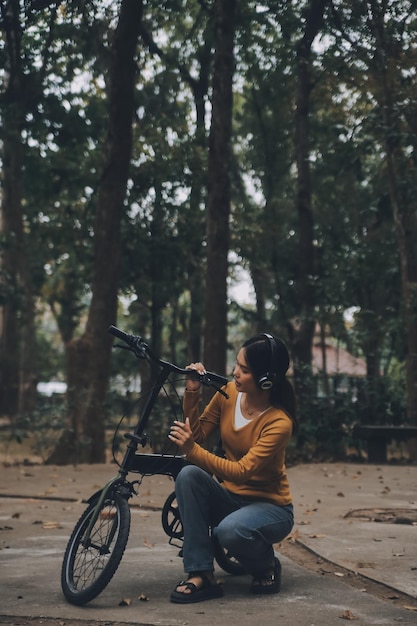 Foto gelukkige jonge aziatische vrouw terwijl ze op een fiets in een stadspark reed ze glimlachte met behulp van de fiets van vervoer milieuvriendelijk concept