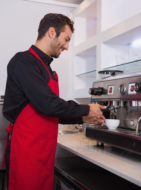 Gelukkige jonge barista die kop van koffie maakt