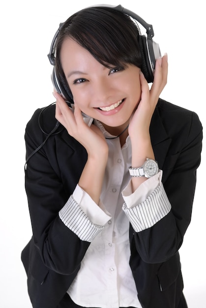 Gelukkige jonge bedrijfsvrouw die van muziek geniet en blije glimlachende uitdrukking toont.