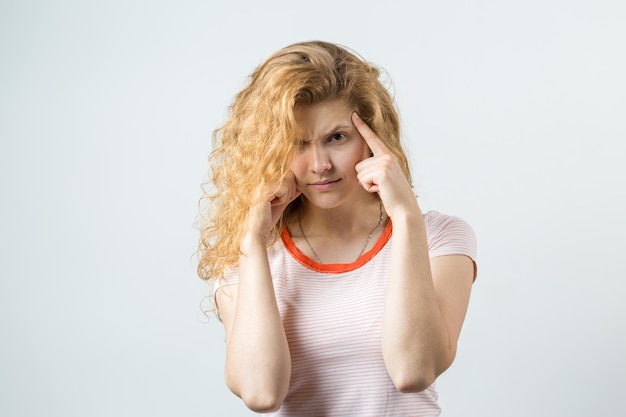 Gelukkige jonge blanke roodharige vrouw in zomershirt kijkt opzij met peinzende uitdrukking en overweegt een plan voor verdere actie