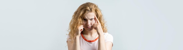 Foto gelukkige jonge blanke roodharige vrouw in zomershirt kijkt opzij met peinzende uitdrukking en overweegt een plan voor verdere actie