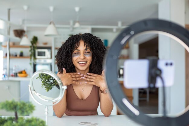 Gelukkige jonge blanke vrouw die een schoonheidsvlog streamt vanuit de maker van online content die een make-up toepast met cosmetische procedure thuis in het interieur van de slaapkamer