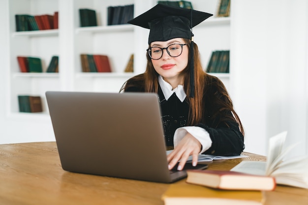 Gelukkige jonge blanke vrouw die universiteitsafstuderen viert tijdens een videogesprek met vriend of familie.