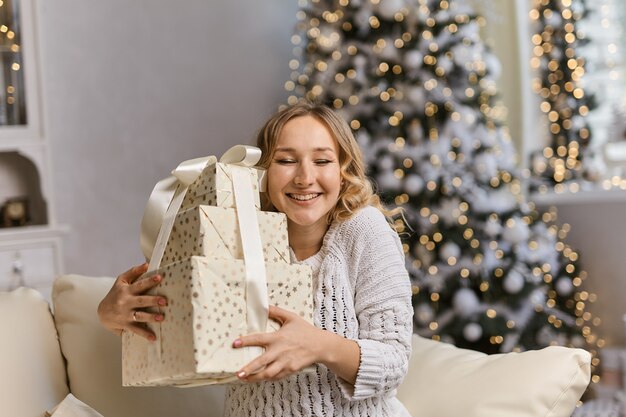 Gelukkige jonge dame die geschenkdoos vasthoudt en omarmt