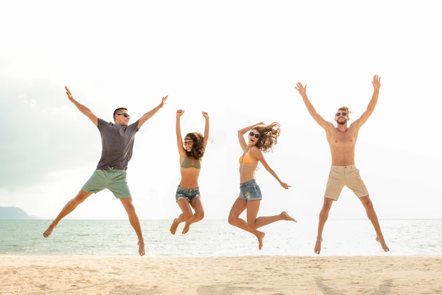 Gelukkige jonge energieke groep vrienden die bij het strand in de zomer springen