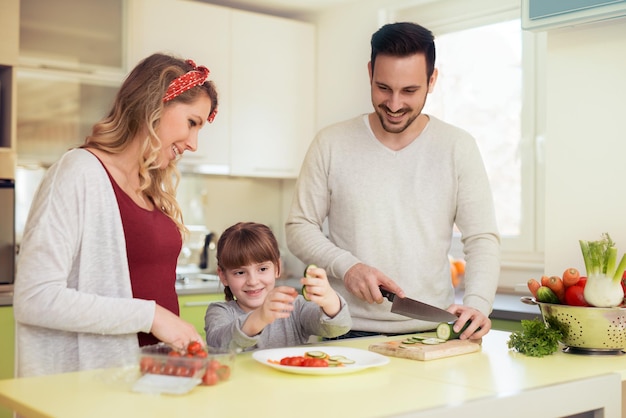 Gelukkige jonge familie die lunch in de keuken voorbereidt