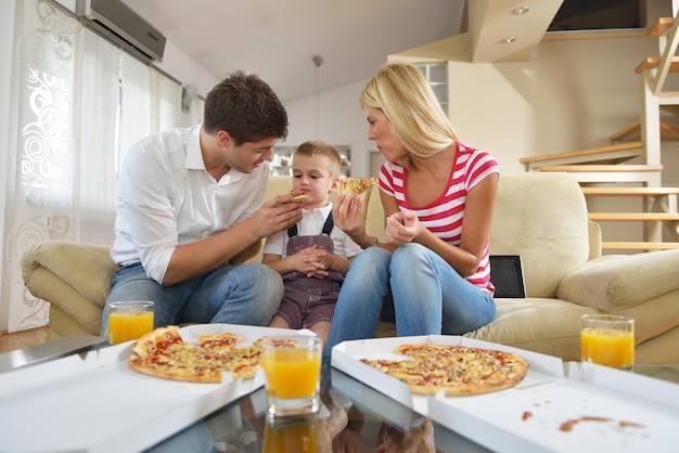 gelukkige jonge familie die smakelijke pizza met cheesa eet en gezond en vers sinaasappelsap drinkt