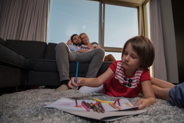 Gelukkige jonge familie die thuis samen op de vloer speelt met een tablet en een tekenset voor kinderen