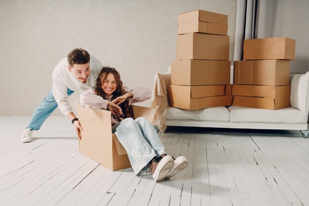 Gelukkige jonge familie echtpaar man draagt vrouw binnen de doos verhuizen met kartonnen dozen naar nieuw landgoed huis appartement concept