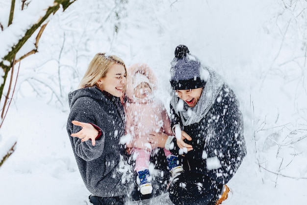 Gelukkige jonge familie loopt met baby op winter straat, moeder, vader, kind