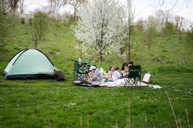 Gelukkige jonge familie moeder en kinderen die plezier hebben en genieten van buiten op picknickdeken schilderen in de tuin lente park ontspanning