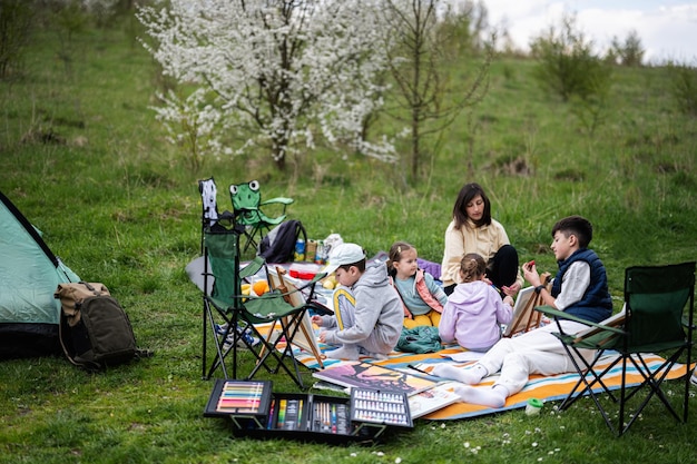 Gelukkige jonge familie moeder en kinderen hebben plezier en genieten van buiten op picknickdeken