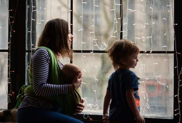 Gelukkige jonge familie mooie moeder met twee kinderen die samen door het raam kijken