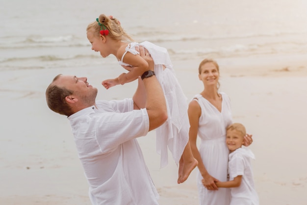 Gelukkige jonge familie op de zonsondergang op het strand.