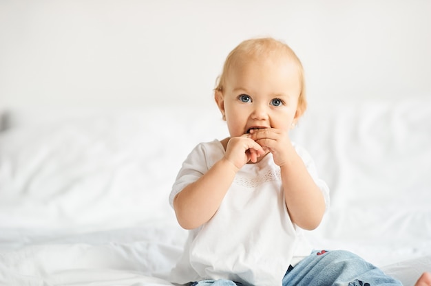 Gelukkige jonge geitjes die in witte slaapkamer spelen. Kleine jongen en meisje, broer en zus spelen op het bed.