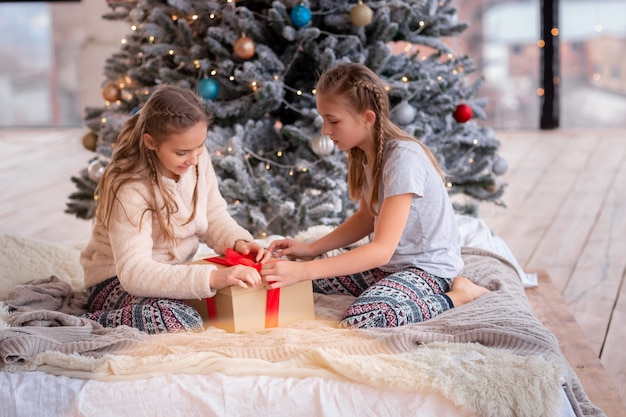 Gelukkige jonge geitjes die pret hebben en cadeautjes in de buurt van de kerstboom openen.