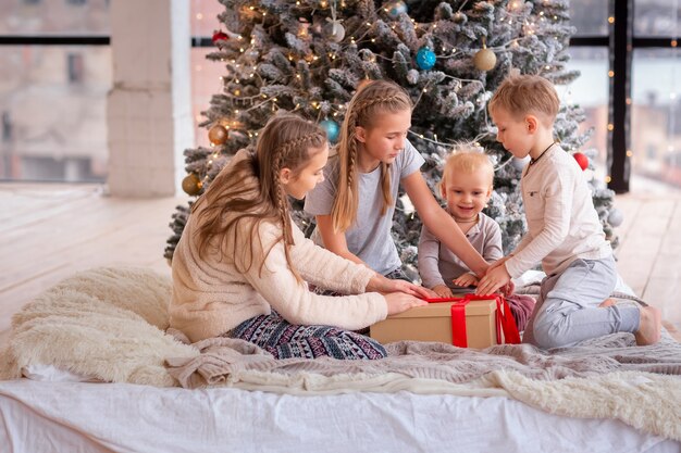 Gelukkige jonge geitjes die pret hebben en cadeautjes in de buurt van de kerstboom openen.