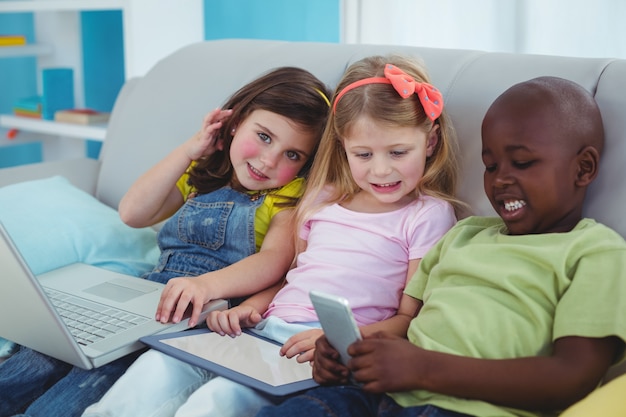 Gelukkige jonge geitjes die samen met een tablet en laptop en een telefoon zitten