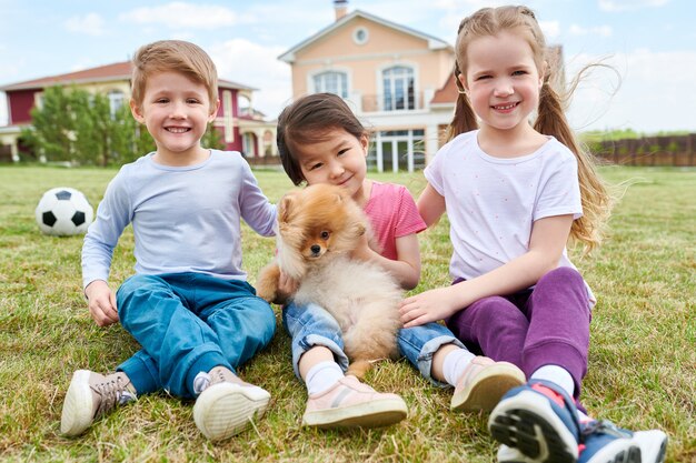 Gelukkige jonge geitjes spelen met puppy